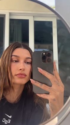 a woman taking a selfie in front of a mirror with her cell phone up to her ear