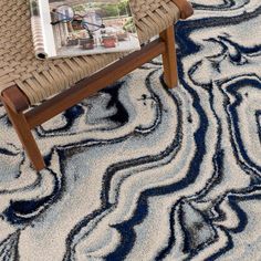 a magazine sitting on top of a wooden chair in front of a rug covered with blue and white swirls