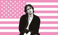 a man sitting on top of a bench in front of a pink and white american flag