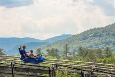 a man and child sitting on top of a blue raft in the middle of mountains