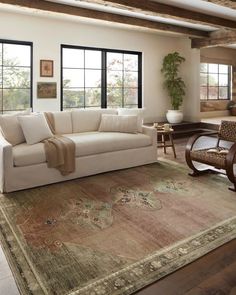 a living room filled with lots of furniture next to large windows and a rug on the floor