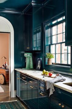 a kitchen with dark green cabinets and white counter tops, along with an arched doorway leading to the bedroom