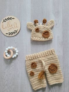 a crocheted baby outfit, rattler and pacifier are laid out on a table