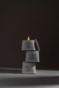 three white boxes stacked on top of each other with a lit candle in the middle