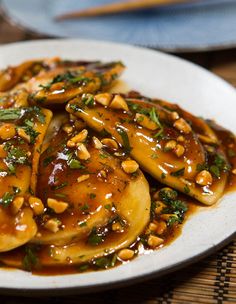 a white plate topped with pancakes covered in sauce and nuts on top of a bamboo mat