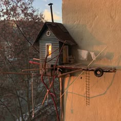 a small house on the side of a building with wires hanging from it's roof