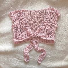 a pink knitted sweater tied up on top of a white bed sheet with a knot at the end