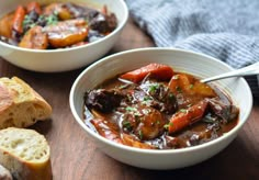 two bowls of stew with bread on the side