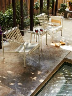 two white chairs sitting next to a swimming pool