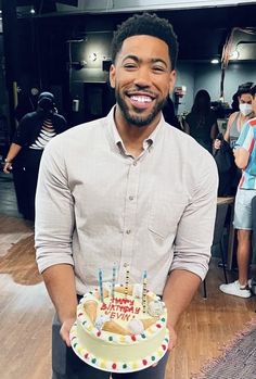 a man holding a birthday cake with candles on it