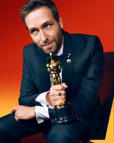 a man in a tuxedo is holding an award for his role in the oscars