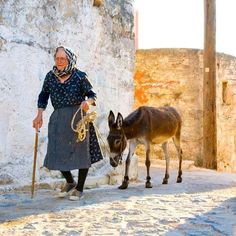 an old woman is walking with a donkey