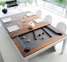 a pool table with balls and cues on it in front of a large glass window