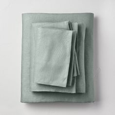 four folded linens in pale green on a white surface with space for text or image