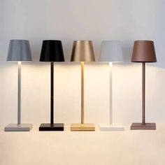 three lamps sitting next to each other on top of a white table with a black lamp in the middle