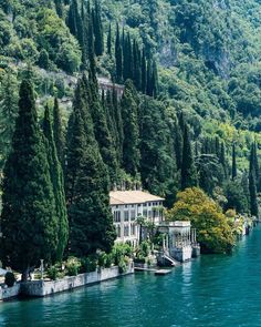 a house on the side of a lake surrounded by trees