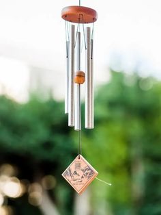 a wind chime hanging from the side of a building with trees in the background