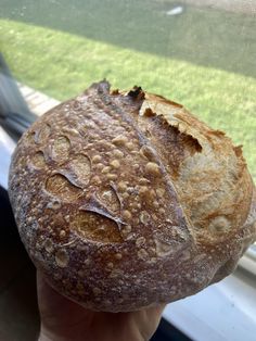 a close up of a person holding a piece of bread in front of a window