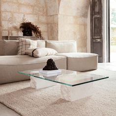 a living room with a white couch and glass coffee table