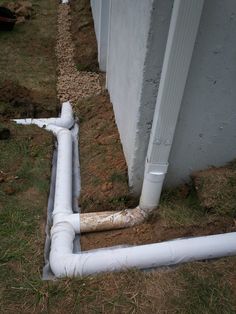 a white pipe laying on the ground next to a building and some grass in front of it