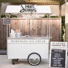 a small ice cream cart sitting in front of a wooden fence