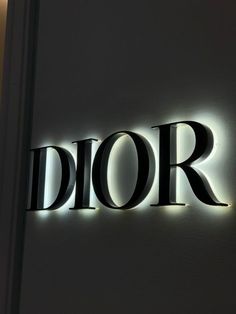 the word dior is lit up in front of a white wall with black lettering