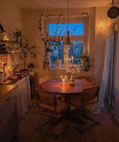 a dining room table with candles on it in front of a window and potted plants