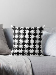 a black and white throw pillow sitting on top of a couch next to two pillows