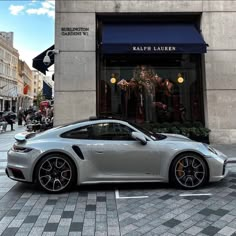 a silver sports car parked in front of a store