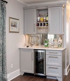 a kitchen with gray cabinets and marble counter tops