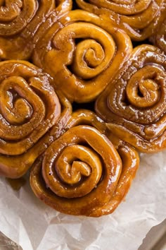 some cinnamon rolls are sitting on top of wax paper