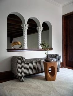 a living room with a couch, mirror and vase on the wall next to it