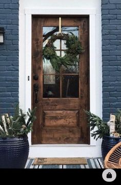 the front door is decorated with wreaths and potted plants