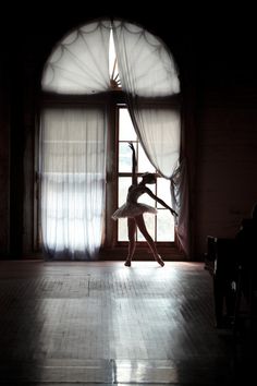 a woman is dancing in front of a window