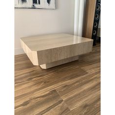 a wooden table sitting on top of a hard wood floor next to a painting hanging on the wall