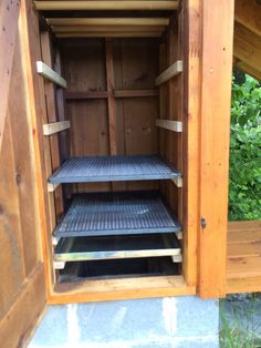 the inside of a wooden storage shed with shelves on each side and one door open