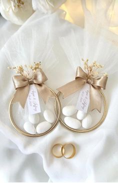 two gold wedding rings with white rocks in the middle and a ribbon tied around them