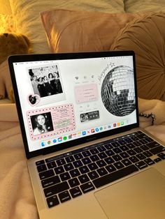 an open laptop computer sitting on top of a bed next to a teddy bear and pillows