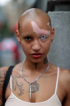 a woman with shaved hair and piercings on her head is looking at the camera