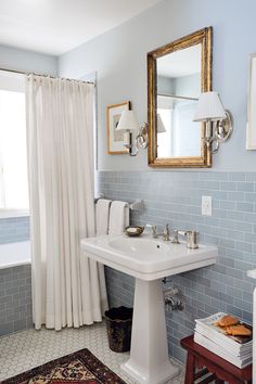 a white sink sitting under a bathroom mirror next to a bathtub and shower curtain