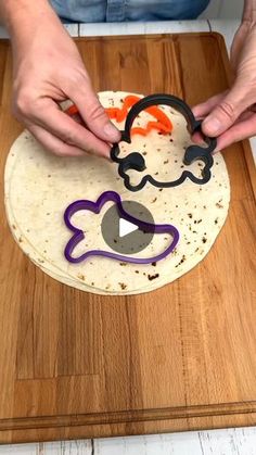 a person cutting into a tortilla with an orange and purple face on it