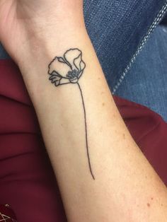 a woman's wrist tattoo with a single flower on the left side of her arm