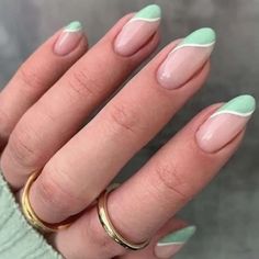 a woman's hand with green and white manies on her nails, wearing gold rings