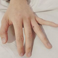 a person's hand with a tiny heart tattoo on their left thumb and finger