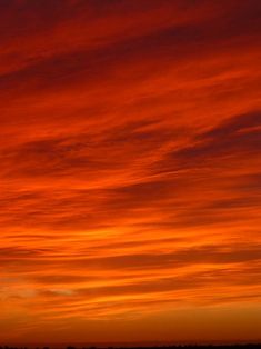 an orange and red sky at sunset with clouds