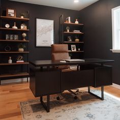 a home office with black walls and shelving on the wall, along with a leather chair