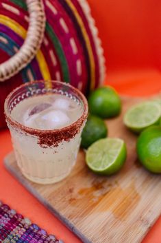 a margarita sitting on top of a cutting board next to limes