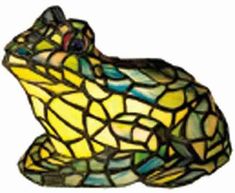 a stained glass frog lamp sitting on top of a white table next to a wall