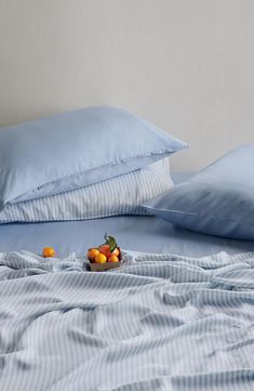 two pillows and some oranges on a bed with blue sheets in front of them