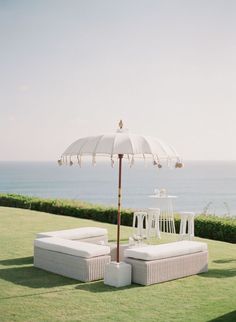 an umbrella sitting on top of a white couch in the middle of a grass covered field